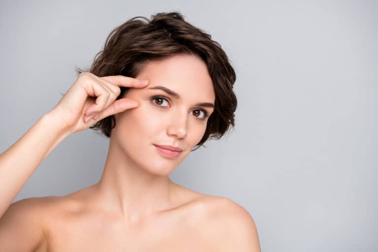 woman with bob haircut lifting brows with fingers