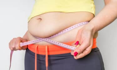 woman using tape measure on body fat